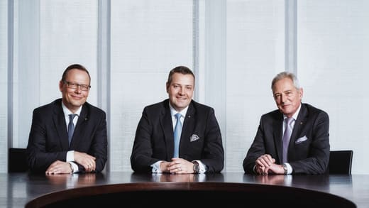 Photo de groupe de trois dirigeants autour d'une table de conseil