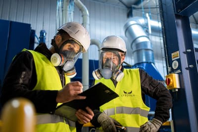 Deux techniciens en équipement de protection consultent un document en atelier