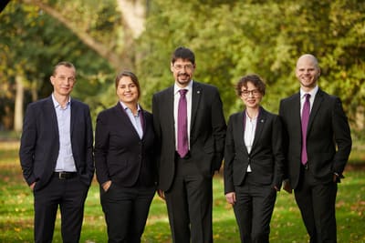 Photo de groupe de cinq collaborateurs en extérieur
